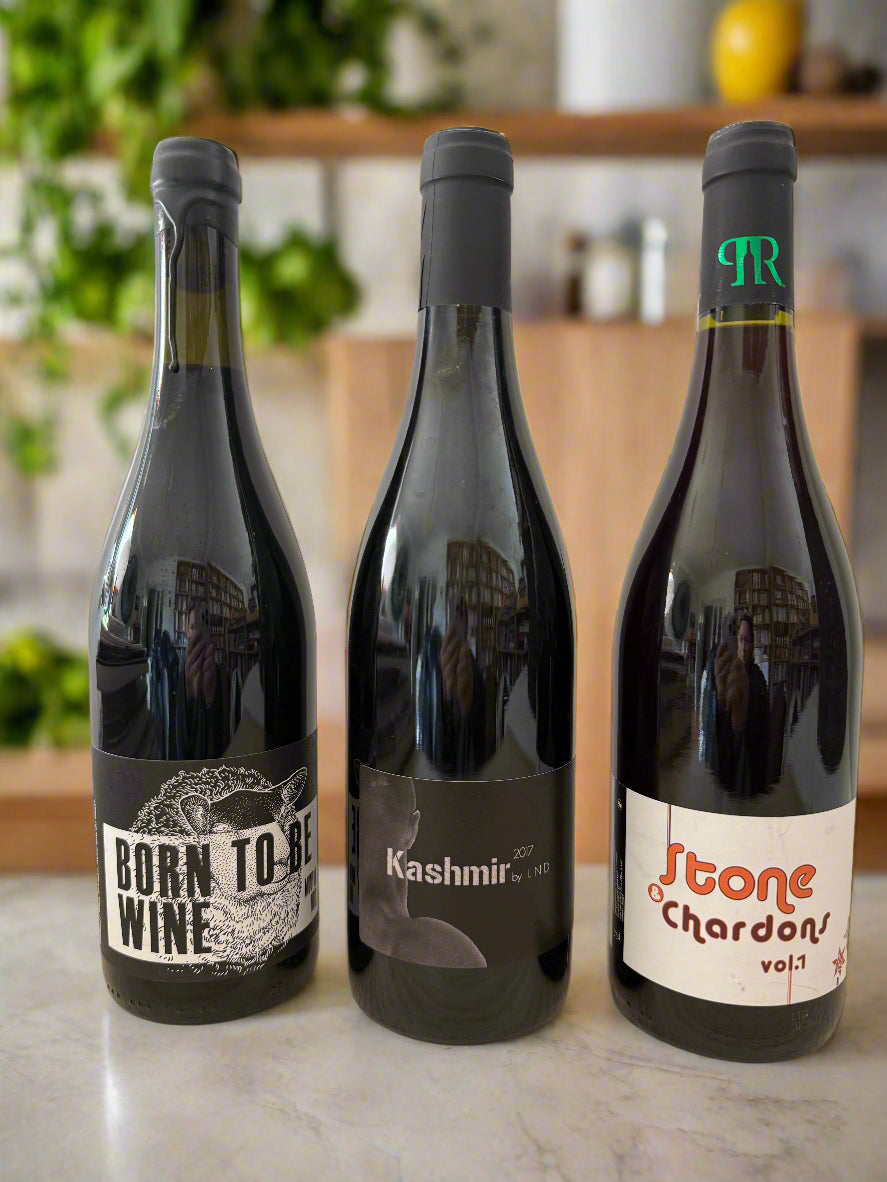 Three bottles of natural red wine—Born To Be Wine, Kashmir, and Stone & Chardons—lined up on a countertop, perfect for BBQ season.