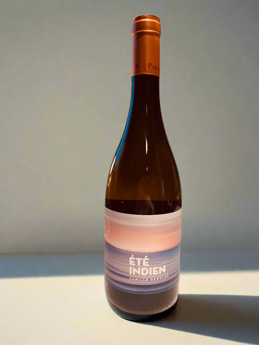 An elegant bottle of Château Paraza orange wine named 'Été Indien', featuring a modern label with soft pastel hues of blue and peach that evoke a serene sunset over the ocean. The label prominently displays the text 'Été Indien Famille Danglas