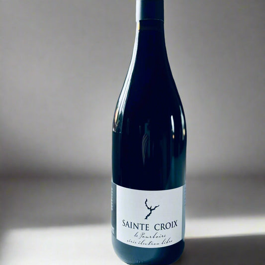 A close-up image of a bottle of Domaine Sainte Croix Pourboire wine, featuring a minimalist label design with blue and white tones, set against a softly blurred background. This is a red biodynamic wine known for its organic production and vibrant flavour profile.