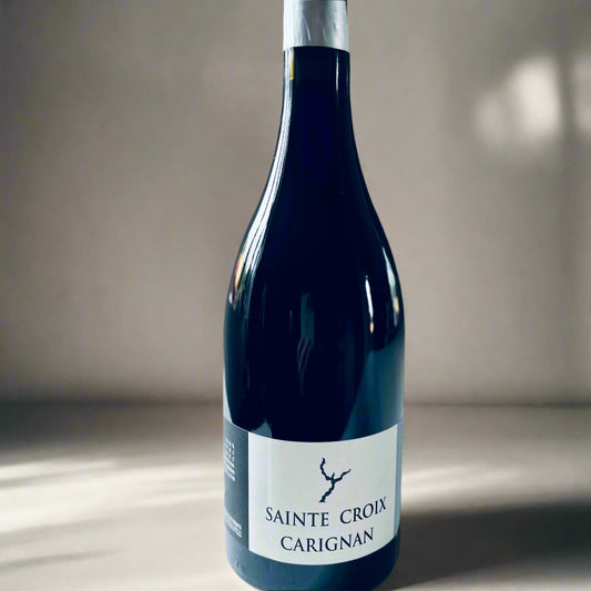 A close-up image of a wine bottle labeled "Sainte Croix Carignan," with a sun lit background, showcasing the elegant design of the bottle.